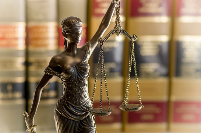 Bronze Lady Justice statue holding scales in law office with legal books in background
